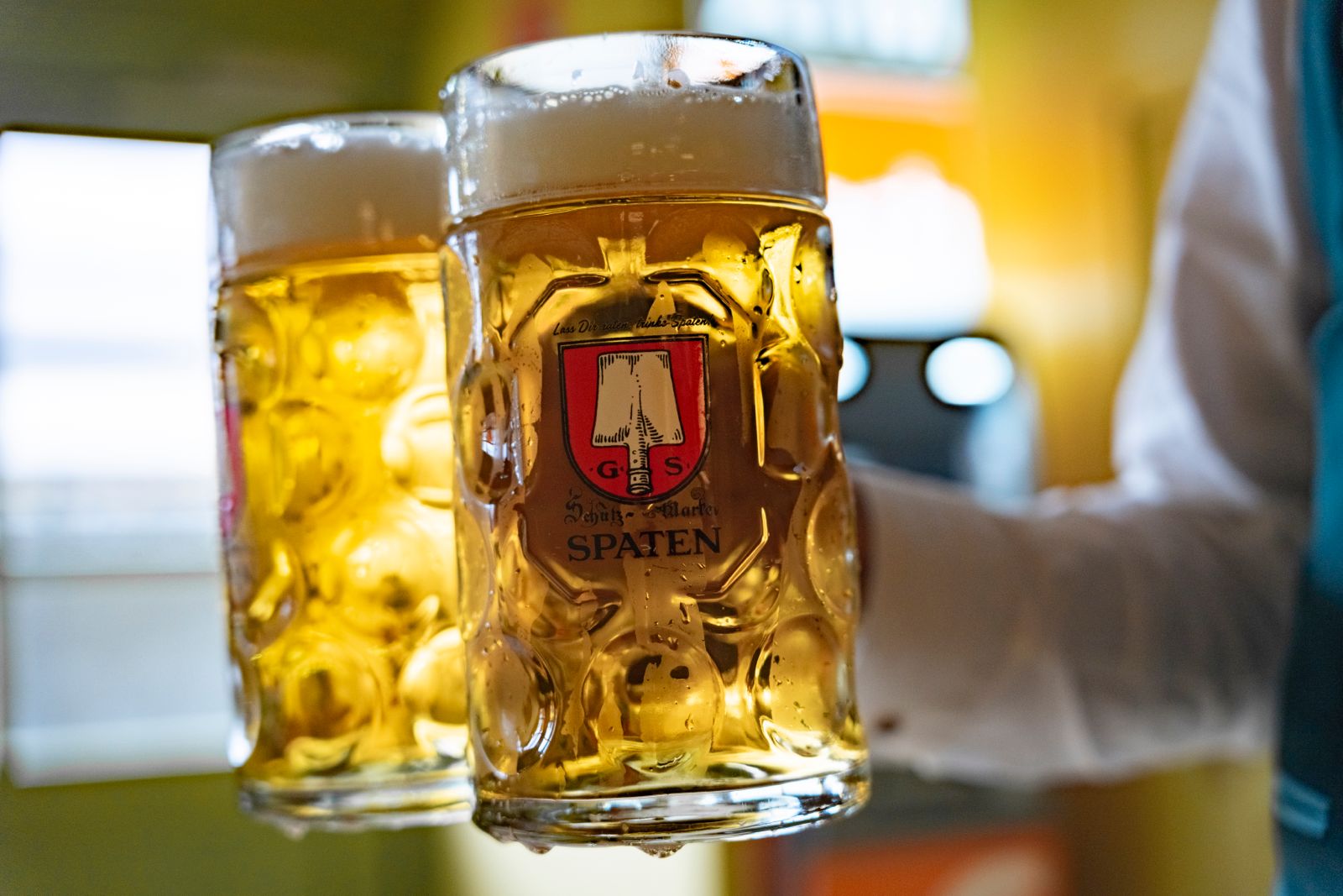 Two freshly poured Spaten beer mugs in a Wiesn atmosphere
